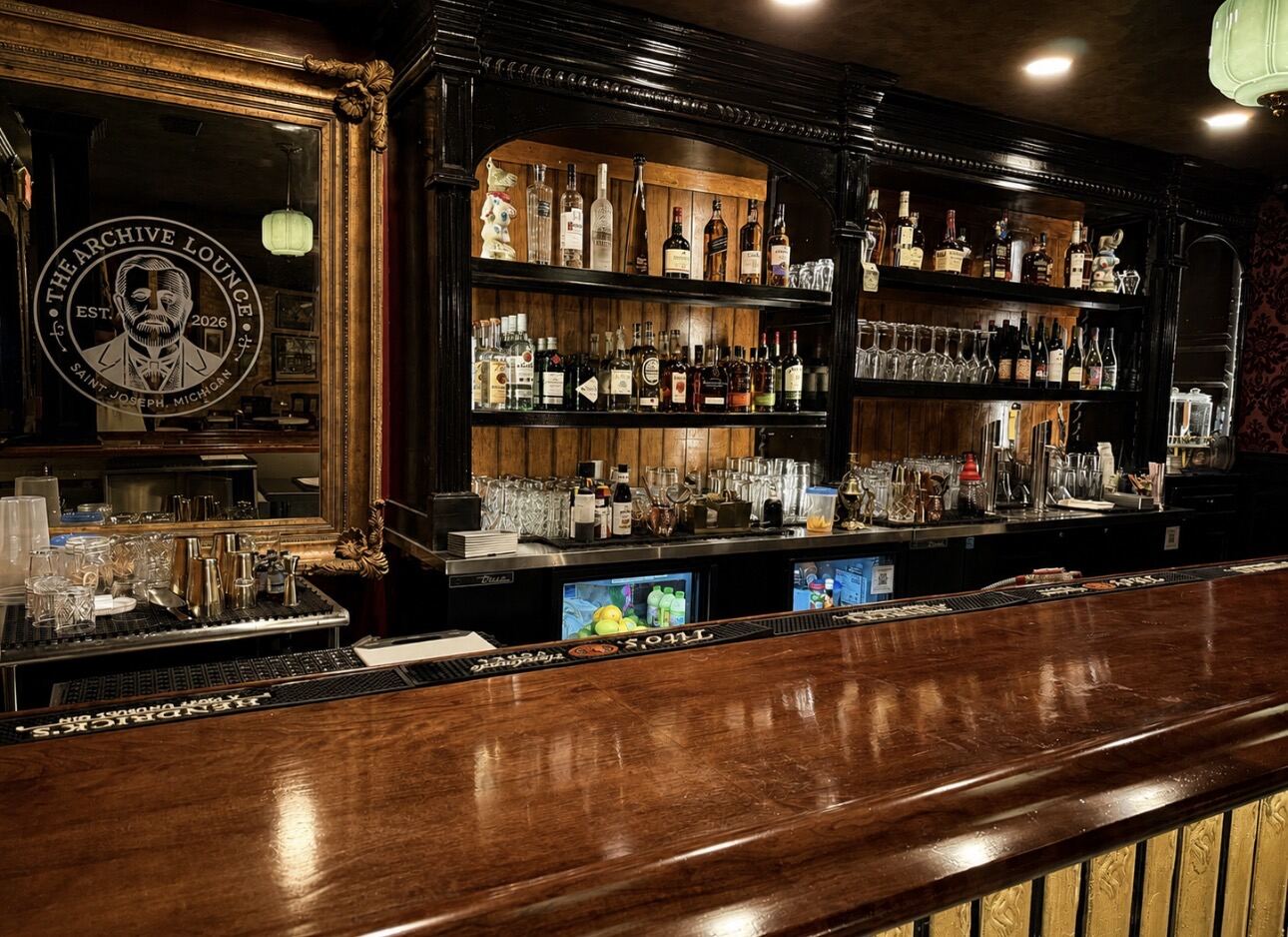 The polished bar and gilded mirror inside The Archive Lounge, a cocktail bar in downtown St. Joseph, Michigan